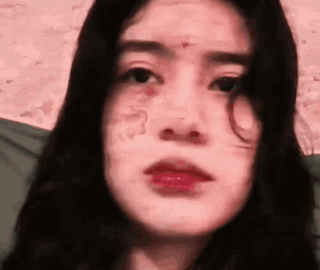 a woman with blood on her face is laying on a bed .