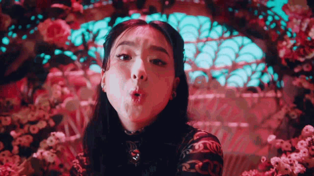 a woman is making a face in front of flowers