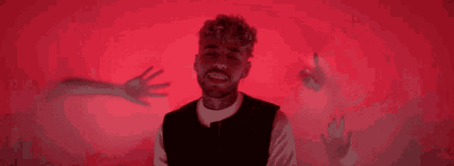a man with a beard stands in front of a red background