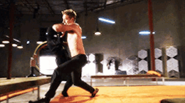 a man without a shirt is boxing another man