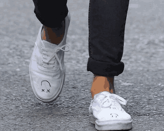 a person wearing a pair of white shoes with a smiley face drawn on them .