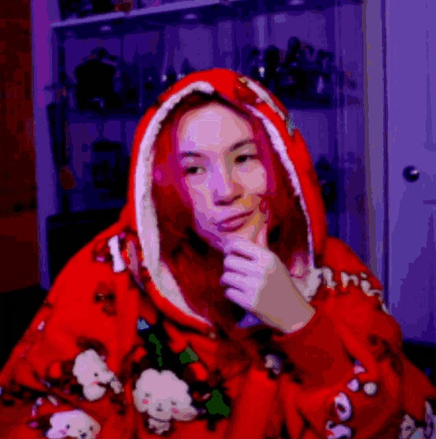a woman with red hair is wearing a red hoodie with a christmas theme