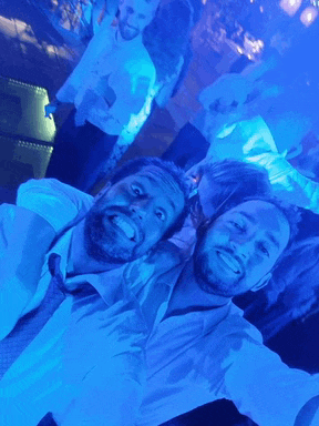 two men are posing for a picture in front of a blue background
