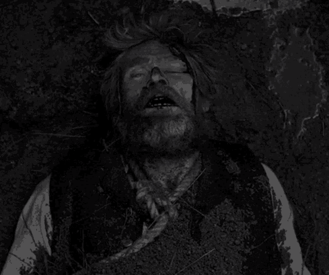 a black and white photo of a man laying in the dirt