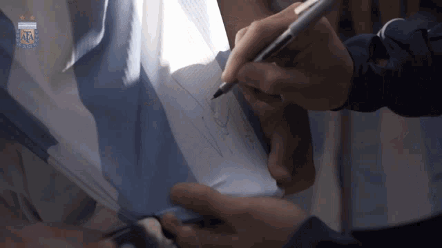 a person signing a piece of paper with a argentina logo