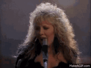 a woman singing into a microphone with makeagif.com written on the bottom