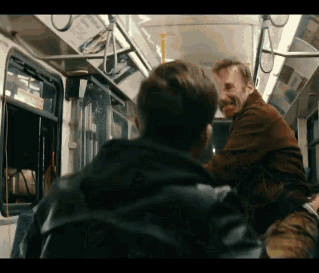 two men are fighting on a bus and one of them has blood on his face .