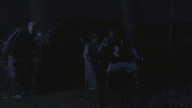 a group of people are standing in the dark with a flashlight