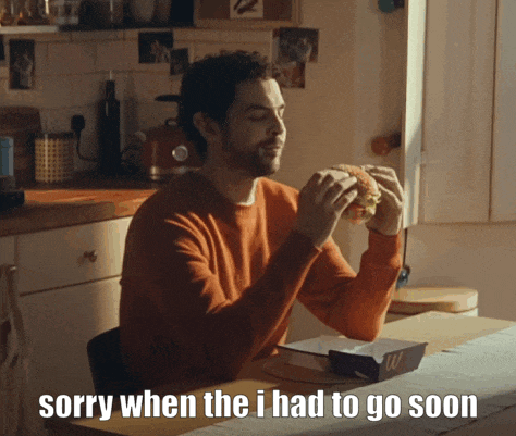 a man is sitting at a table eating a hamburger with the words sorry when the i had to go soon below him