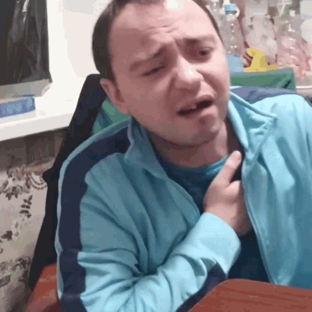a man in a blue jacket is making a face