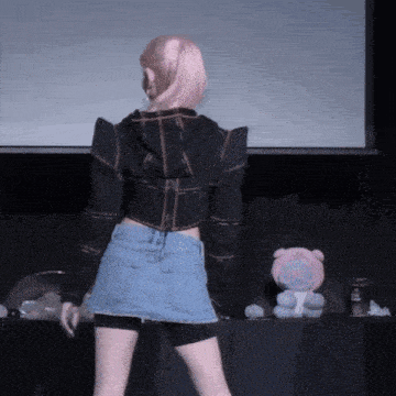 a woman in a denim skirt is standing in front of a teddy bear