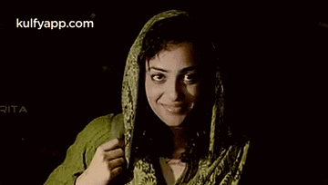 a woman wearing a green scarf around her head is smiling and looking at the camera .