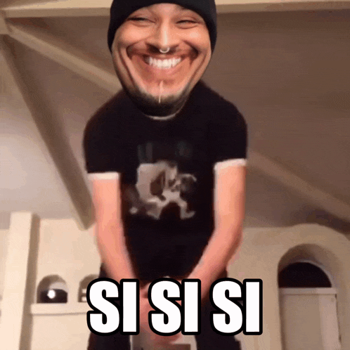 a man wearing a black shirt and a black beanie is smiling with the words sisisi written on his chest