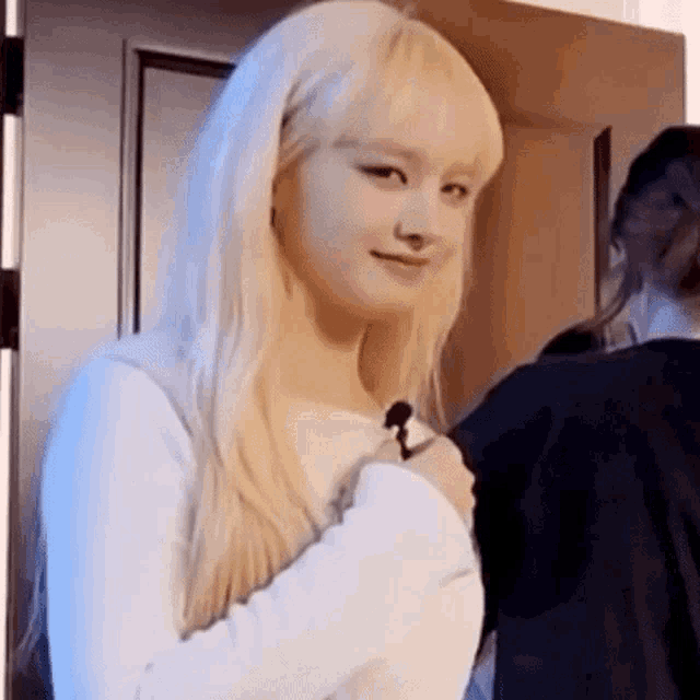 a woman with blonde hair is standing in front of a door holding something in her hand .