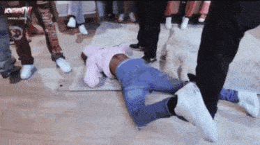a group of people are standing around a person laying on the floor with a sign above them that says ' nowthis tv '