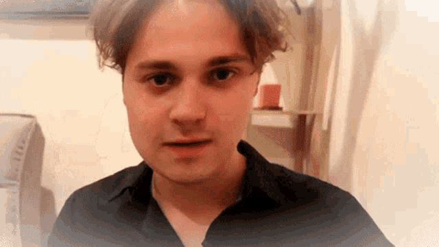 a man in a black shirt looks at the camera