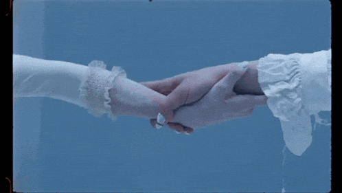 a woman in a white dress holds another woman 's hand against a blue background