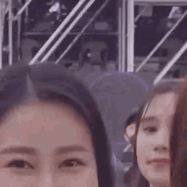 a close up of a woman 's face looking at the camera while standing next to another woman .