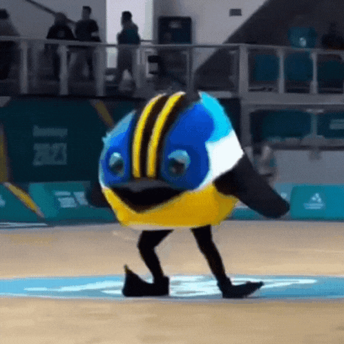 a mascot dressed as a bird is walking on a basketball court .
