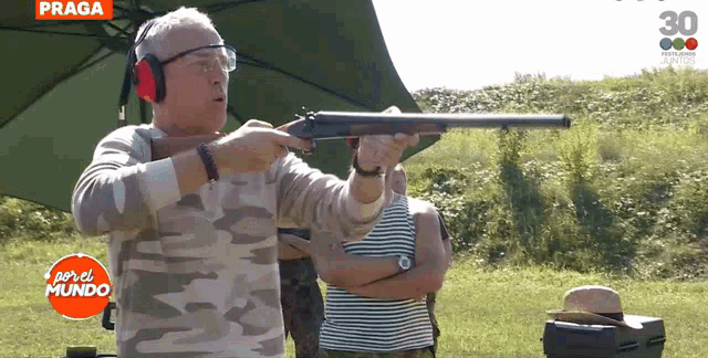 a man is holding a shotgun in front of a sign that says praga on it