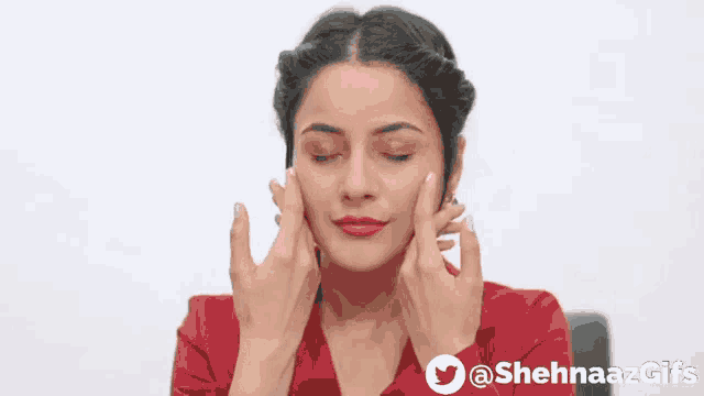 a woman in a red shirt is touching her face .