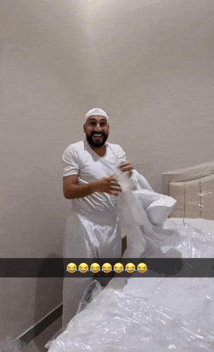 a man in a white shirt is standing next to a bed with a plastic bag on it
