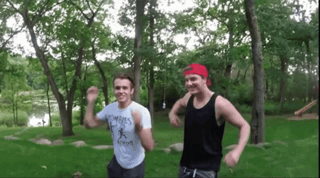 a man in a zombies shirt is standing next to another man in a black tank top