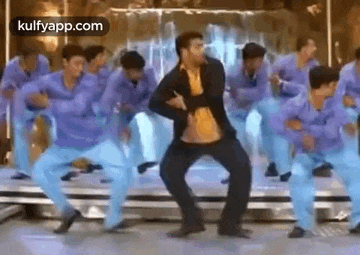 a man is dancing on a stage with a group of dancers .