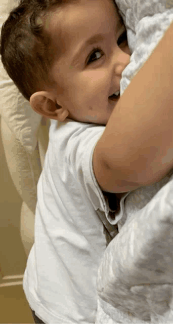 a little boy in a white shirt is being held by someone
