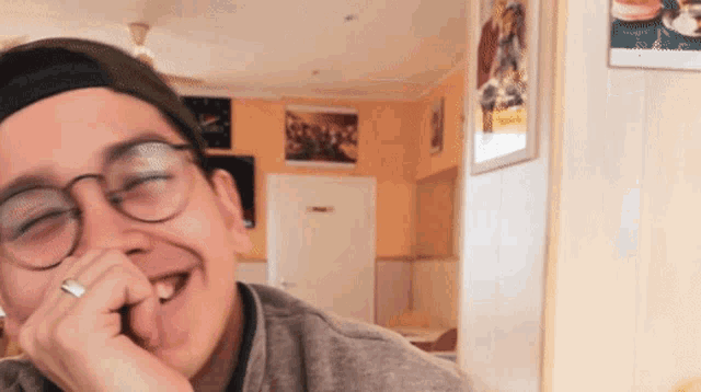 a man with glasses and a ring on his finger smiles