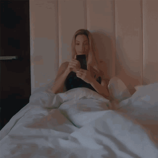 a woman is sitting on a bed with a cup of coffee in her hand