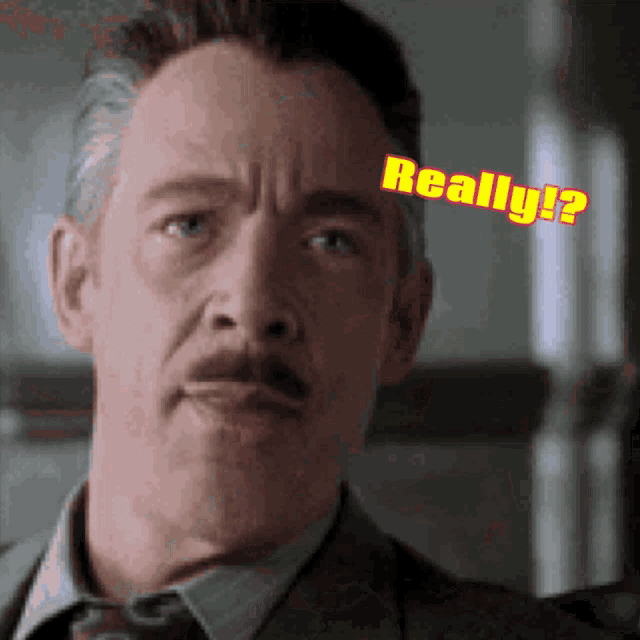 a man with a mustache is wearing a suit and tie and has the word really written on his face .