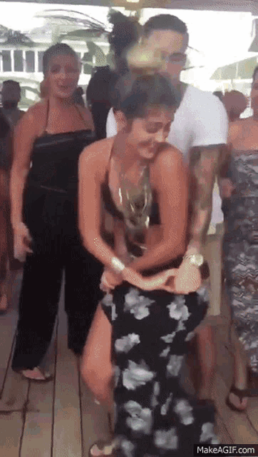 a woman in a bikini is dancing with a group of people .