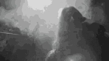 it is a black and white photo of a person smoking a cigarette .