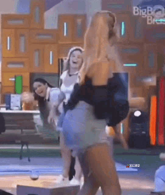 a group of women are dancing on a stage with a big brother logo in the background