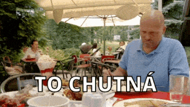 a bald man sits at a table with a plate of food and a glass of water with the words to chutina written on the table