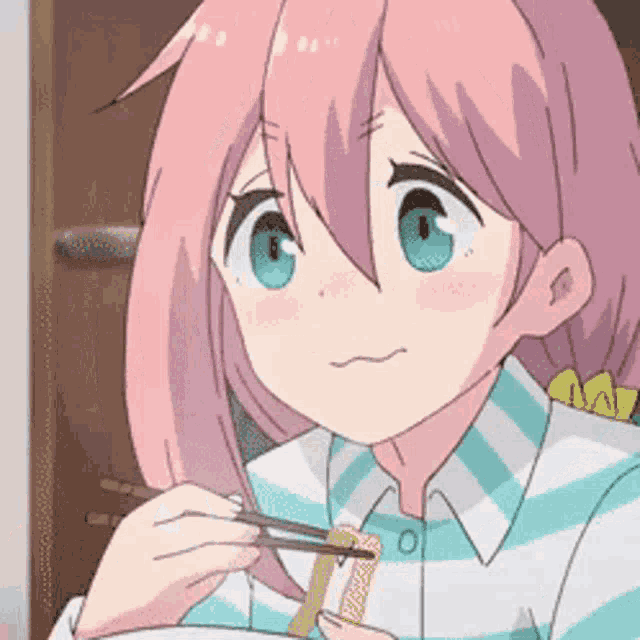 a girl with pink hair is eating food with chopsticks .