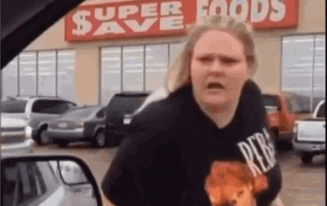 a woman in a black shirt is standing in front of a supermarket .