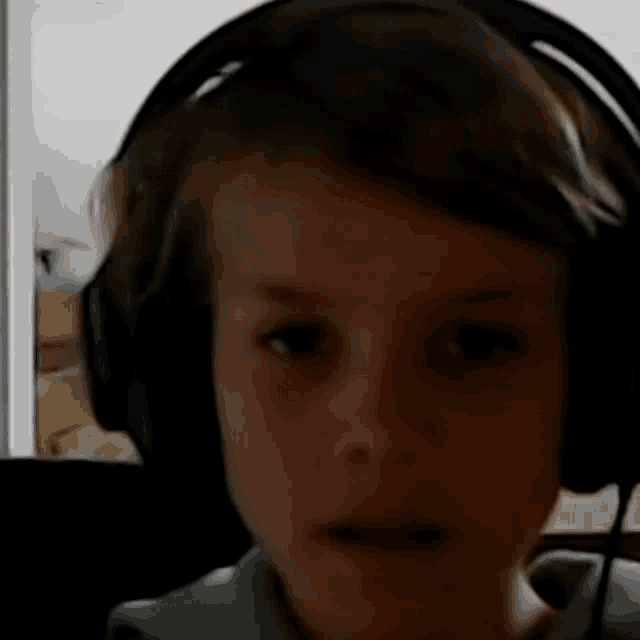 a young boy wearing headphones looks at the camera with a serious look on his face