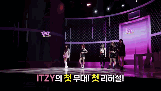 a group of girls standing on a stage with itzy written on the bottom left