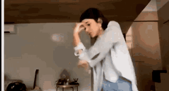 a woman is standing in a room holding her head .