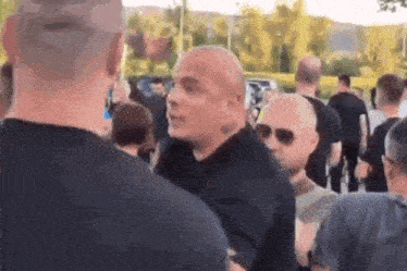 a group of men are standing in a line talking to each other in a crowd .