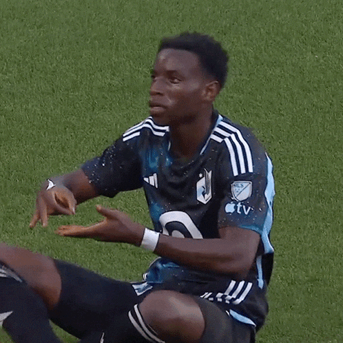 a soccer player is kneeling down on the field wearing a jersey that says apple tv on it