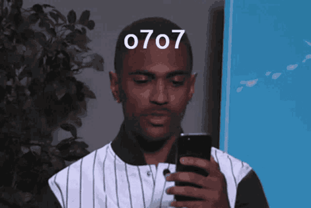 a man is looking at his phone with the number 0707 on his forehead