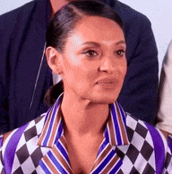 a woman in a purple and white checkered shirt is sitting in a room with other people .