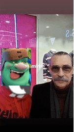a man with a mustache and glasses is standing in front of a store window with a picture of a cartoon character .
