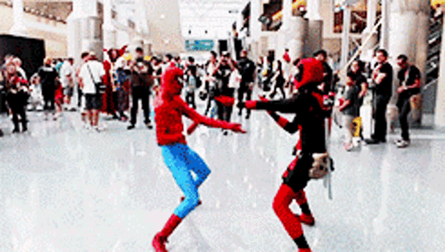 two people in spiderman and deadpool costumes are dancing in front of a crowd