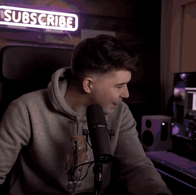 a man sitting in front of a microphone with the words fuck off on the bottom