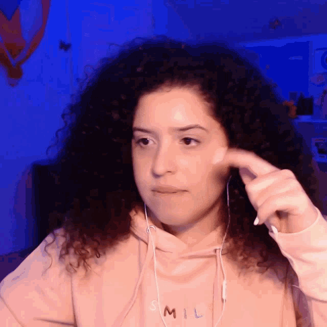a woman with curly hair is wearing a hoodie that says smil on it