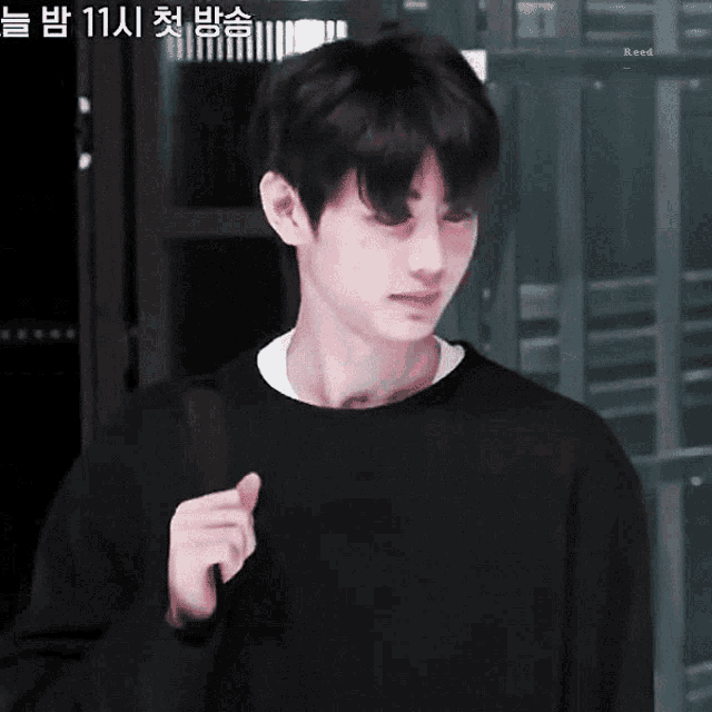 a young man wearing a black sweater is holding a black bag